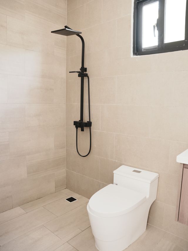 Baño terminado en Villas Waves con ducha de lluvia negra mate y revestimiento beige