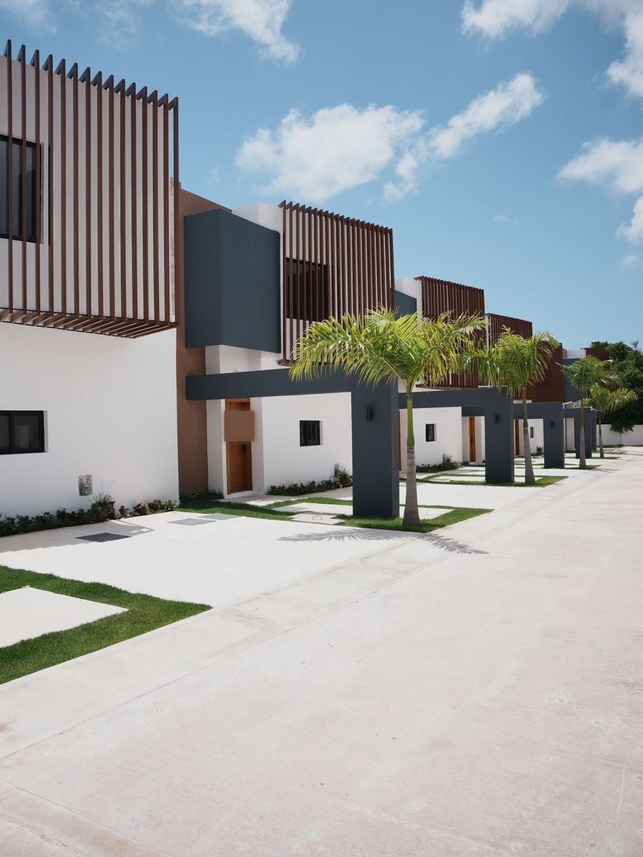 Villas Dreams en Bávaro: calle interior de townhouses terminados con celosías de madera, palmas y jardines