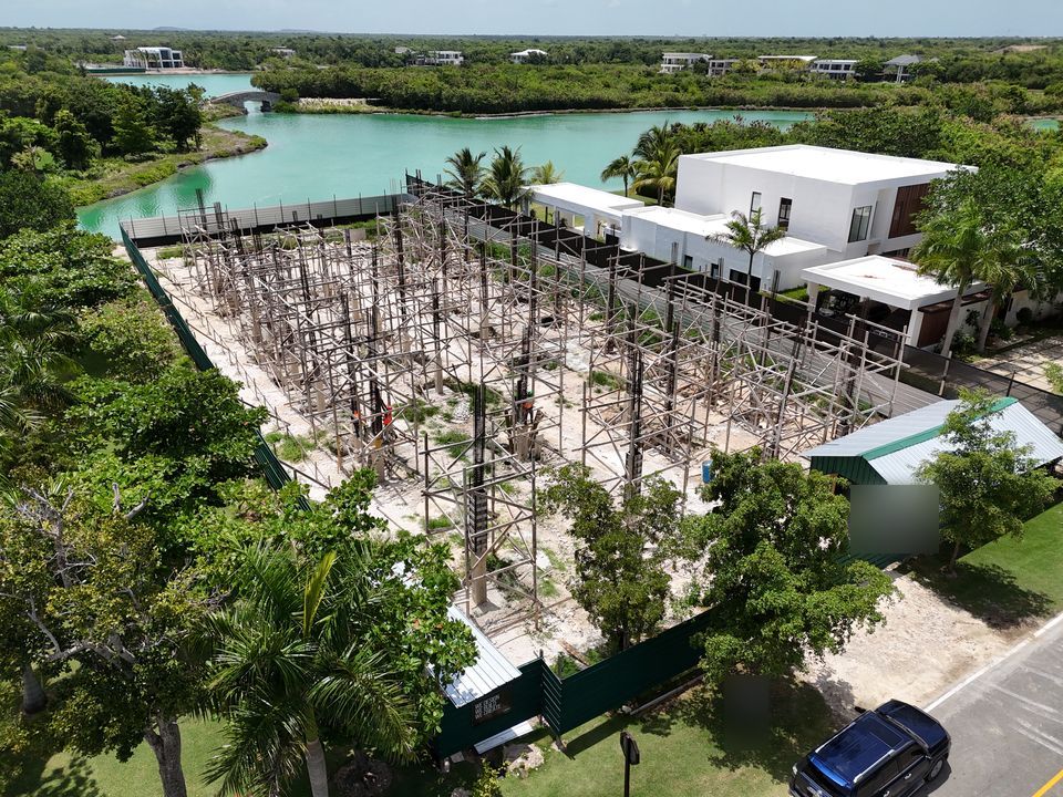 Vista aérea de una villa en obra gris junto a una laguna turquesa en Lagos Punta Cana